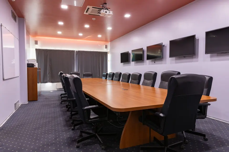 Sala za sastanke Orao s dugim stolom, kožnim stolicama i LCD ekranima na zidu