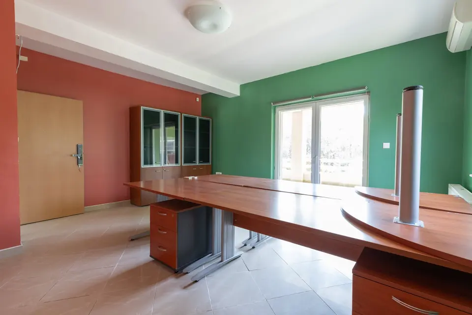 Office with a long desk, a cabinet and large windows